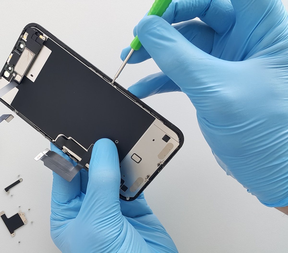 Técnico con guantes trabajando en el interior de un celular sobre el banco de trabajo